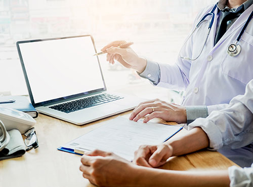 Doctor reviewing information on a laptop to illustrate elements in the annual MDVIP Wellness Program Plus.